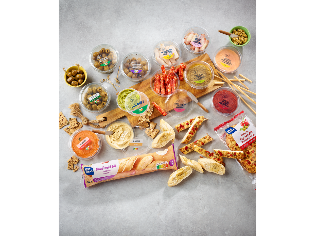 Houmous Chef Select, guacamole, olives et divers apéritifs sur une planche en bois.