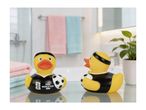 Two rubber ducks in black jerseys with a football, in a bathroom setting.