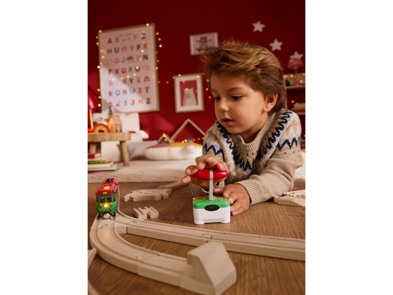A child plays with a Lupilu remote control train on a wooden track.