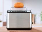 Тостер SilverCrest с поставка за притопляне на хлебче върху дървена маса.