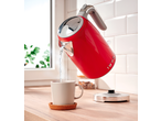 Red SILVERCREST® kettle pouring water into a mug on a wooden counter.