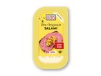 Gul pakke med salami på rugbrød, pyntet med krydderurter og sprøde løg.