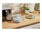 A SilverCrest microwave, a rice cooker, and a plate of rice with vegetables on a wooden kitchen counter.