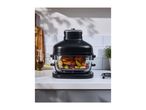 Black air fryer with chicken and vegetables on a kitchen counter
