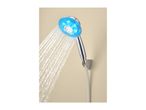 Handheld shower head with blue LED lights and water spraying out, mounted on a beige wall.