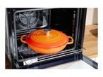 An orange SilverCrest Dutch oven sits on a rack inside an open oven.