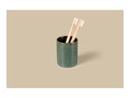 Two bamboo toothbrushes in a green ceramic holder on a beige background.