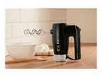 Black hand mixer with a dough hook on a kitchen counter next to a bowl and eggs