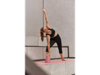 Woman practicing yoga outdoors with block and mat.