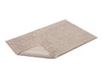 A beige bath mat with a textured surface is shown folded on a white background.