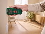 Човек държи зелен мултифункционален детектор Parkside®, използван върху бежова стена.