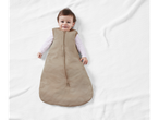 Happy baby in a beige striped sleep sack on a white textured blanket.