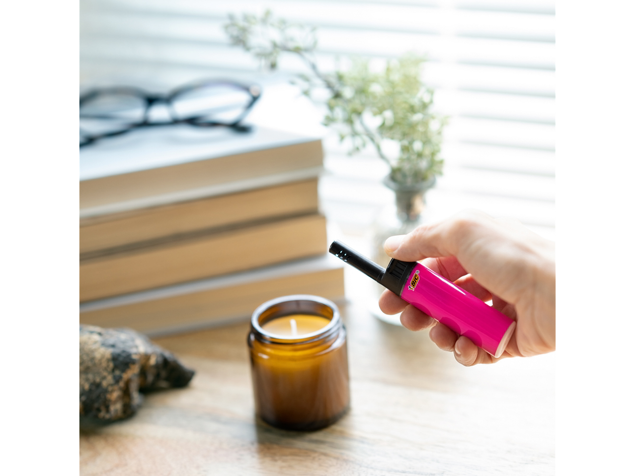 BIC lighter and candle on a wooden table.