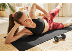 Femeie făcând exerciții cu gantere Crivit de 2 kg pe un covor de yoga.