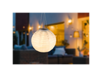 Solarna lampa u obliku papirne fenjerke visi u pozadini sa prijatnom baštenskom atmosferom.
