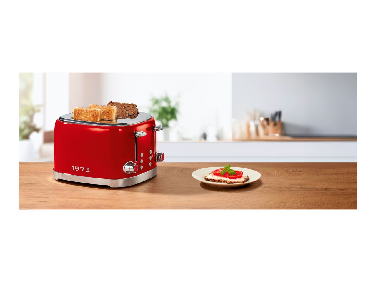 Red retro toaster with four slots on a wooden table next to a prepared toast
