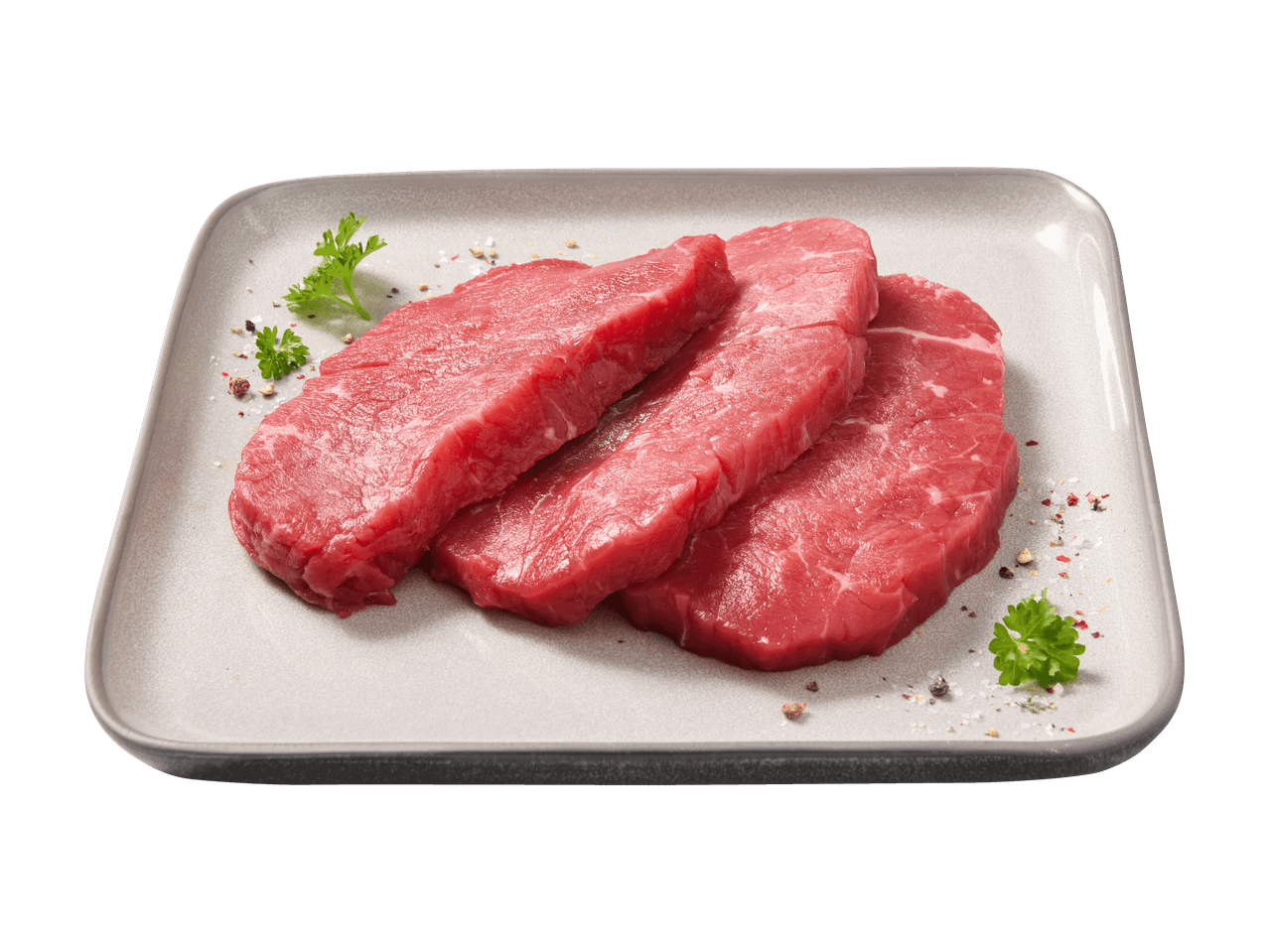 Drei rohe Rindersteaks mit Petersilie und Gewürzen auf einer grauen Platte.