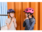 Twee kinderen met CRIVIT fietshelmen, een blauwe en een roze, met LED-licht.