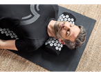 Un bărbat se relaxează pe un covor de yoga cu o pernă de acupresură.