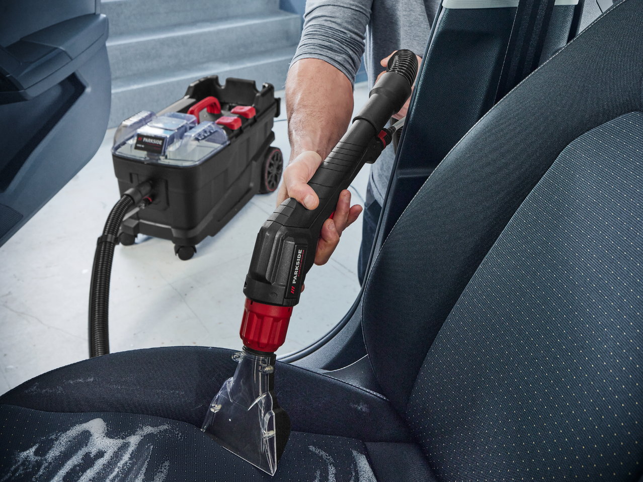 Мъж почиства седалка на кола с прахосмукачка Parkside