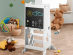 Ein weißes Kinder-Maltisch mit Kreidezeichnungen in einem Spielzimmer mit Spielzeug.