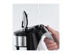 A hand pouring water into a black and silver kettle with an open lid.