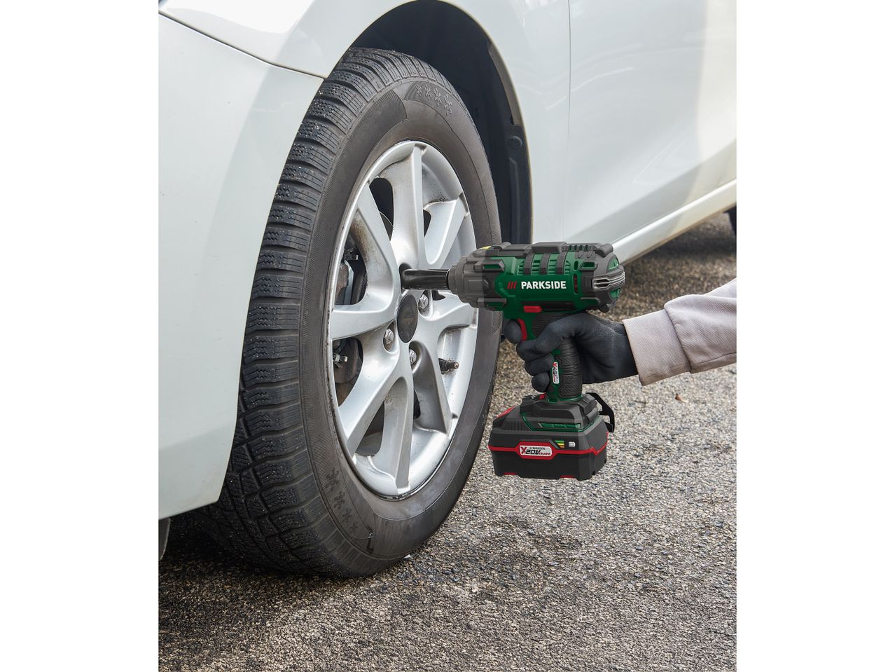 A person using a Parkside impact wrench to change a car tire.