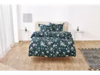Set de lenjerie de pat floral turcoaz cu perne asortate pe un pat într-o cameră luminoasă.