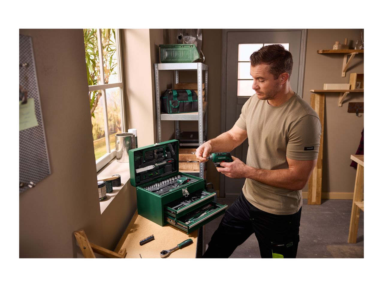 Man assembling a screwdriver with a tool box and other tools on a workbench.