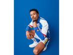 Man in a white, blue, red, and yellow tracksuit with matching socks and white sneakers.
