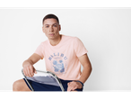 Model masculin cu tricou roz Malibu și pantaloni scurți.