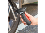 Hand holding a digital tire pressure gauge, displaying 33.5 PSI, on a car tire.
