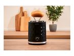 Black toaster with integrated warming rack holding a bread roll on a wooden table
