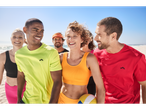 Group of friends smiling on the beach in sportswear.