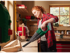 Woman using a Parkside 20V cordless handheld vacuum cleaner to clean sawdust in a workshop.