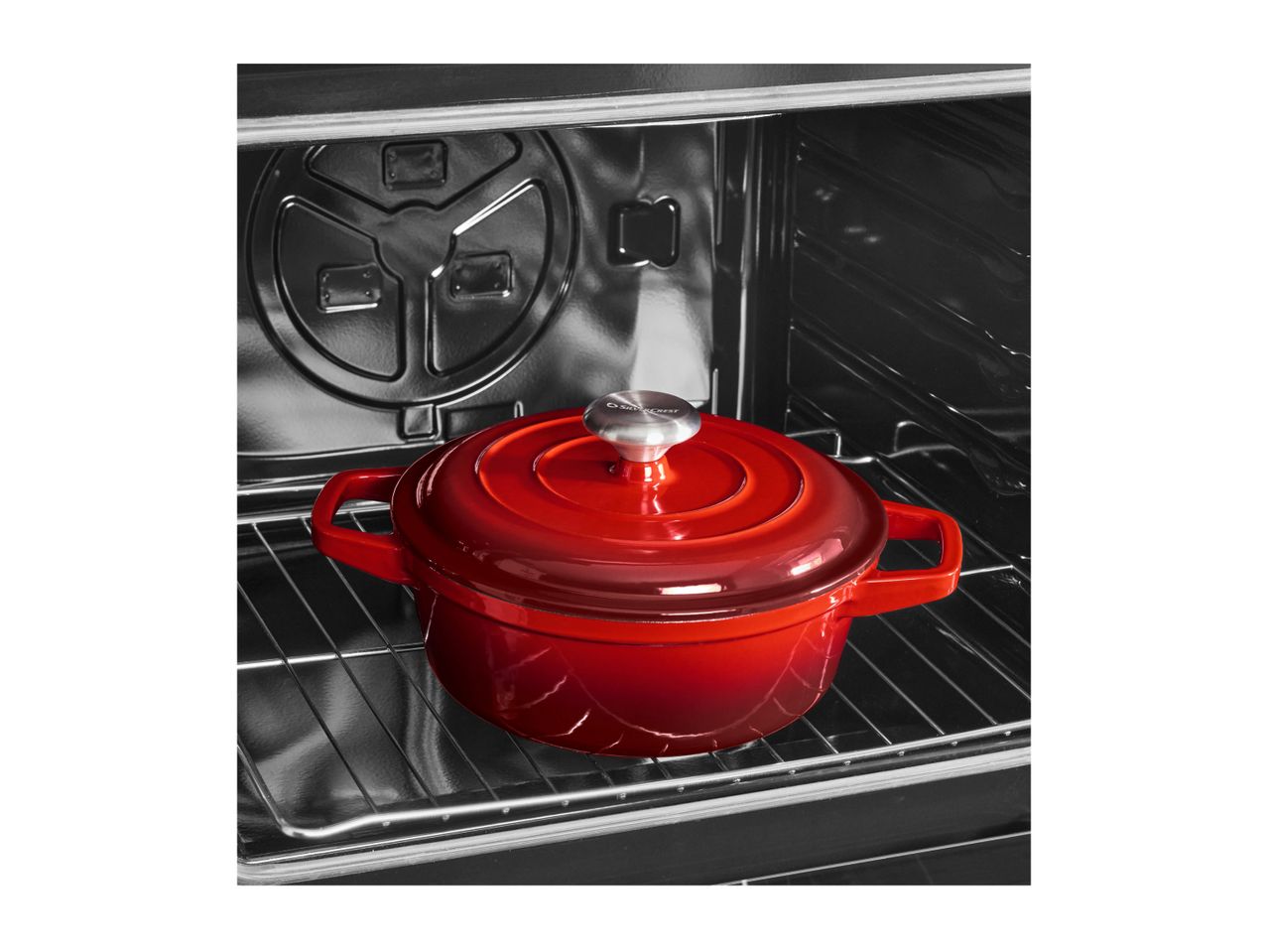 Red cast iron pot with lid inside an oven on a metal rack.