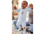 Baby in light blue acorn-themed sleepwear, held by an adult.