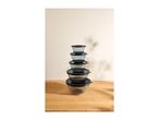 A stack of five clear glass mixing bowls with black lids on a wooden surface.