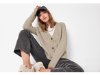 Woman in esmara® chunky knit cardigan, white t-shirt, dark jeans, and cap.