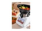 A white Monsieur Cuisine Smart food processor with a black steamer attachment filled with vegetables.
