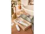 A white facial hair remover and accessories on a tray next to a sink with soap and a plant.