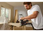 A man uses a Parkside jigsaw with vacuum attachment to cut a piece of wood.