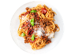 Spaghetti bolognese with grated cheese, sun-dried tomatoes, and basil leaves on a white plate.