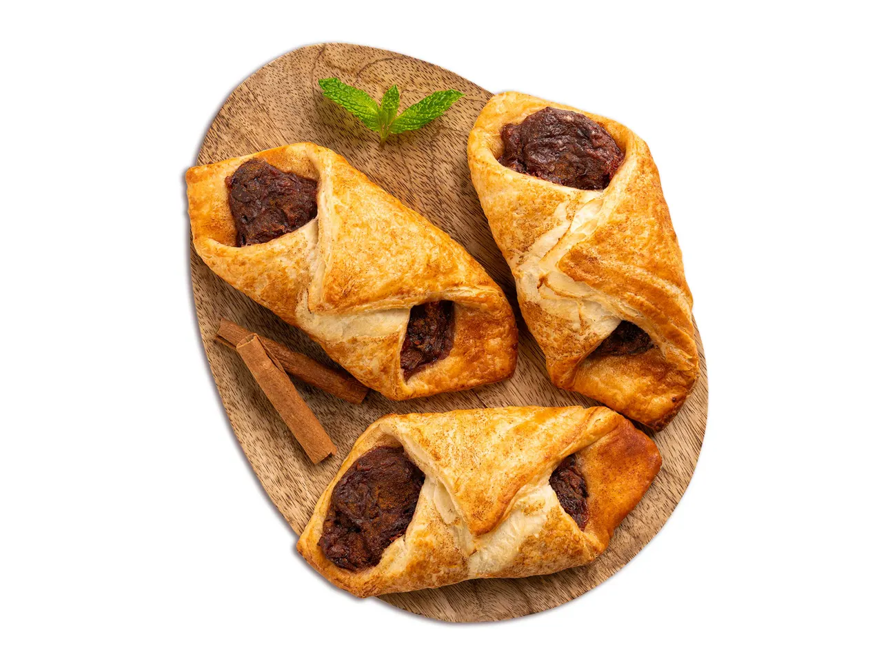 Három fahéjas-almás táska fahéjrúddal és mentával egy fa tálcán.