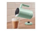 Mint green milk frother pouring foam into a glass of coffee on a wooden counter.