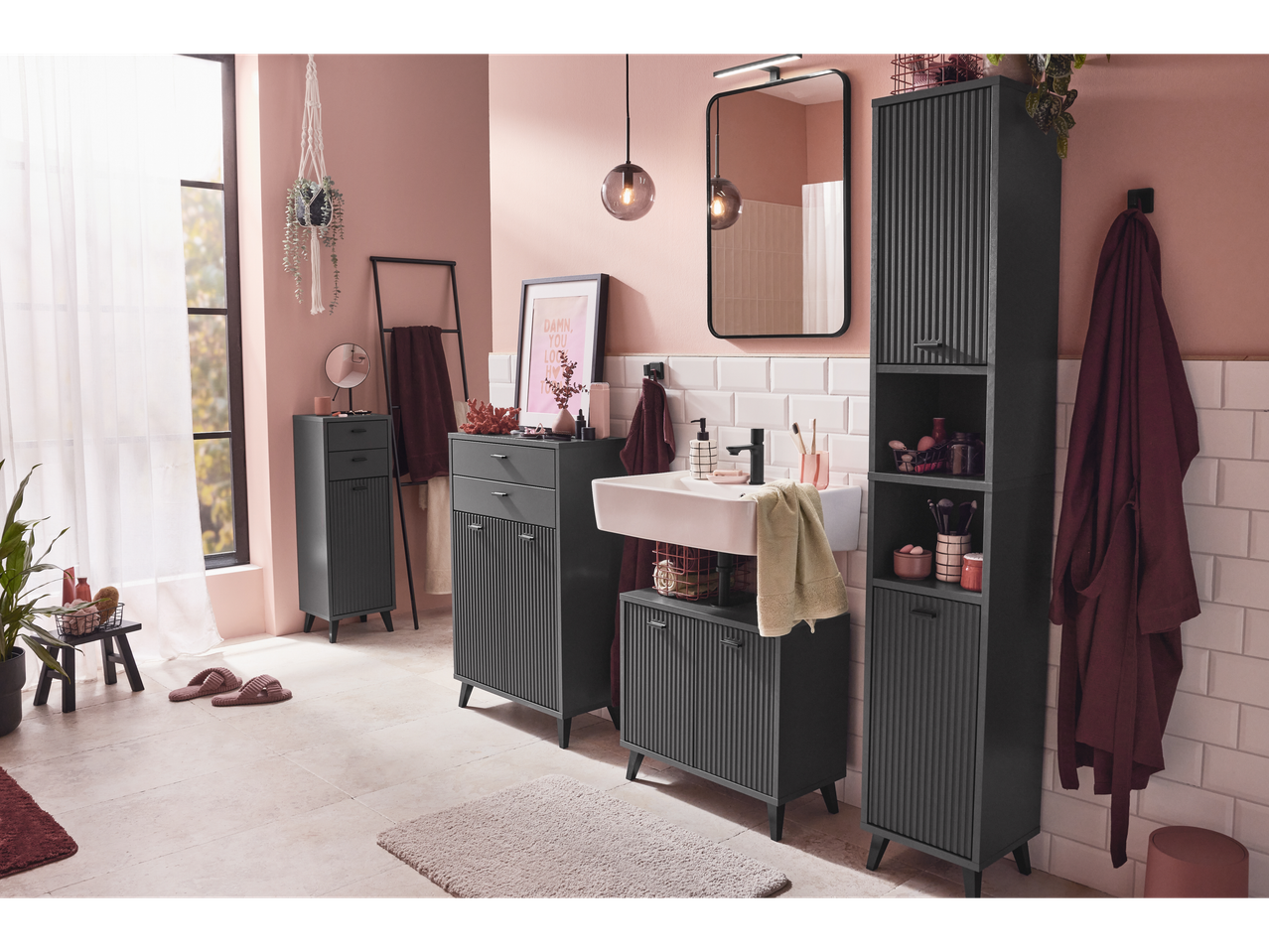 Baie modernă cu mobilier gri închis, chiuvetă albă și accesorii roz.
