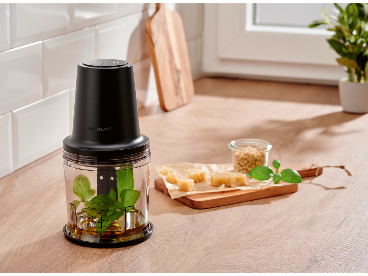 SILVERCREST® Mini Chopper with basil, oil, cheese, and pine nuts on a kitchen counter.