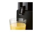 Close-up of a black juicer next to a glass of orange juice.