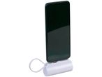 A black smartphone is charging on a white cylindrical power bank.