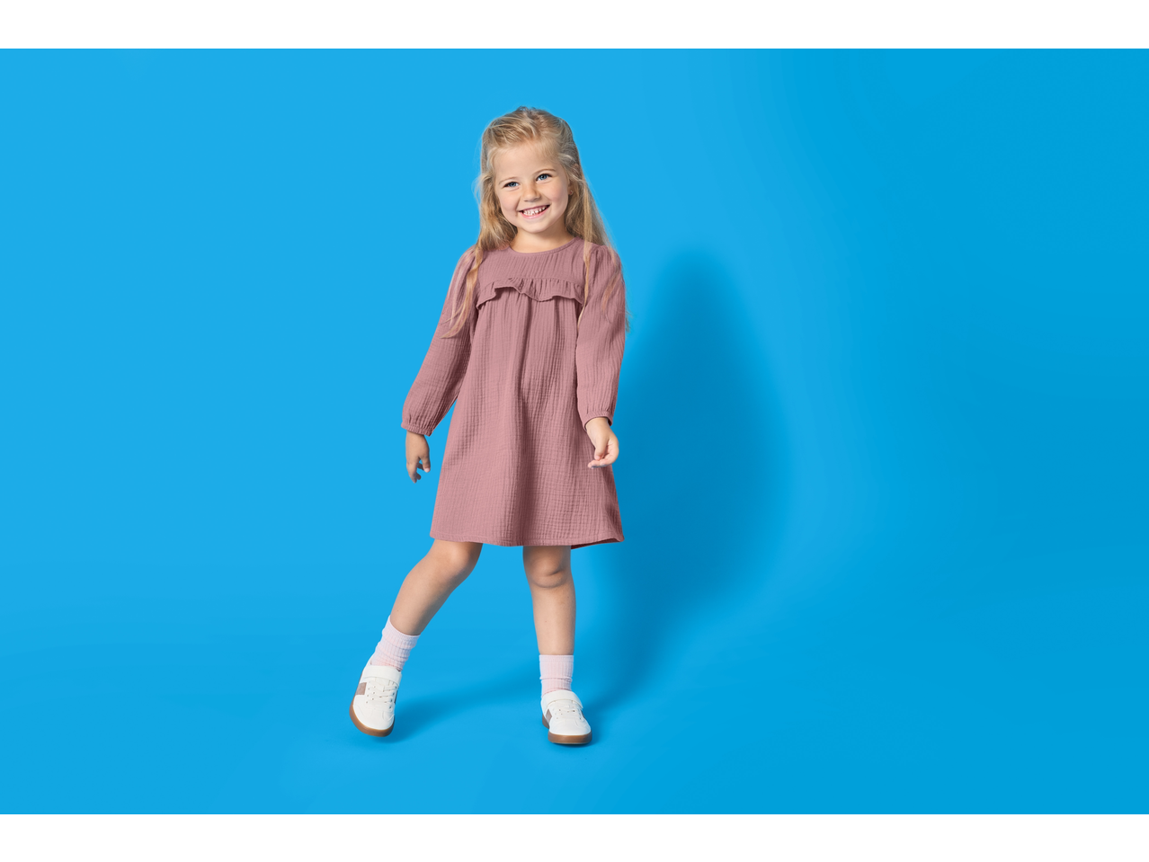 Fetiță în rochie de muselină LUPILU, 2 piese, zâmbind.